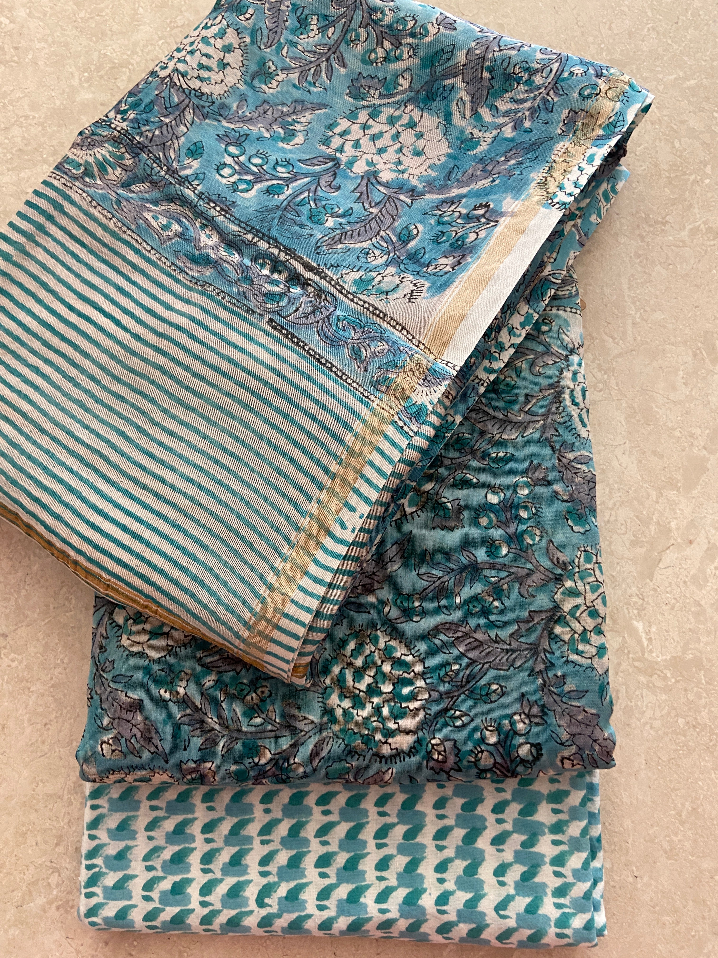 Stacked view of Peacock Blue Chanderi 3-piece suit - striped dupatta on top, peacock blue kurta with padded motifs in middle, teal geometric pant at bottom - complete unstitched Chanderi handloom set, Madhya Pradesh | Bloomton Designs