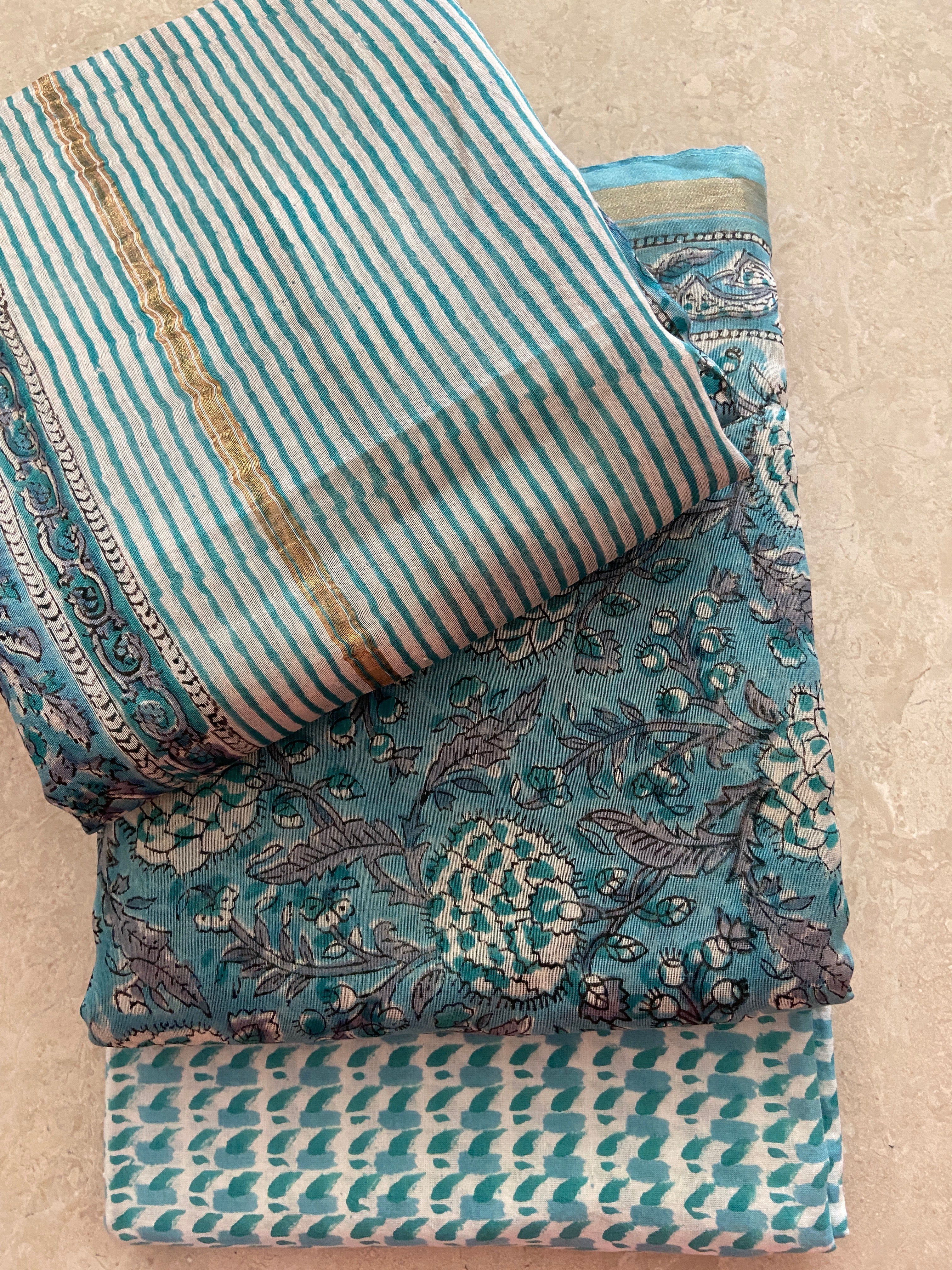 Flat lay of Peacock Blue Chanderi 3-piece suit - grey and cream striped dupatta with gold zari border, peacock blue kurta with padded geometric motifs, teal geometric print pant - Chanderi handloom, Madhya Pradesh | Bloomton Designs