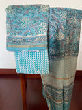 Peacock blue Chanderi handloom 3-piece suit draped on chair - kurta with padded geometric motifs in cream and gold, striped dupatta with teal and gold borders - unstitched from Chanderi, Madhya Pradesh | Bloomton Designs
